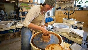 A female student working with clay at a pottery wheel