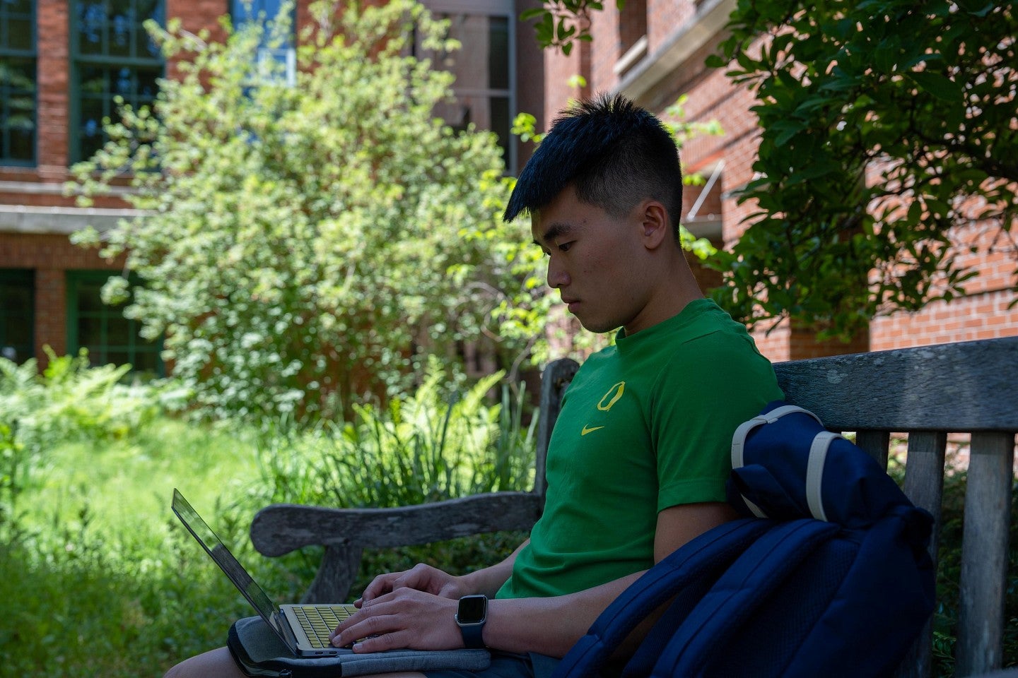 international student looks at laptop while sitting on bench