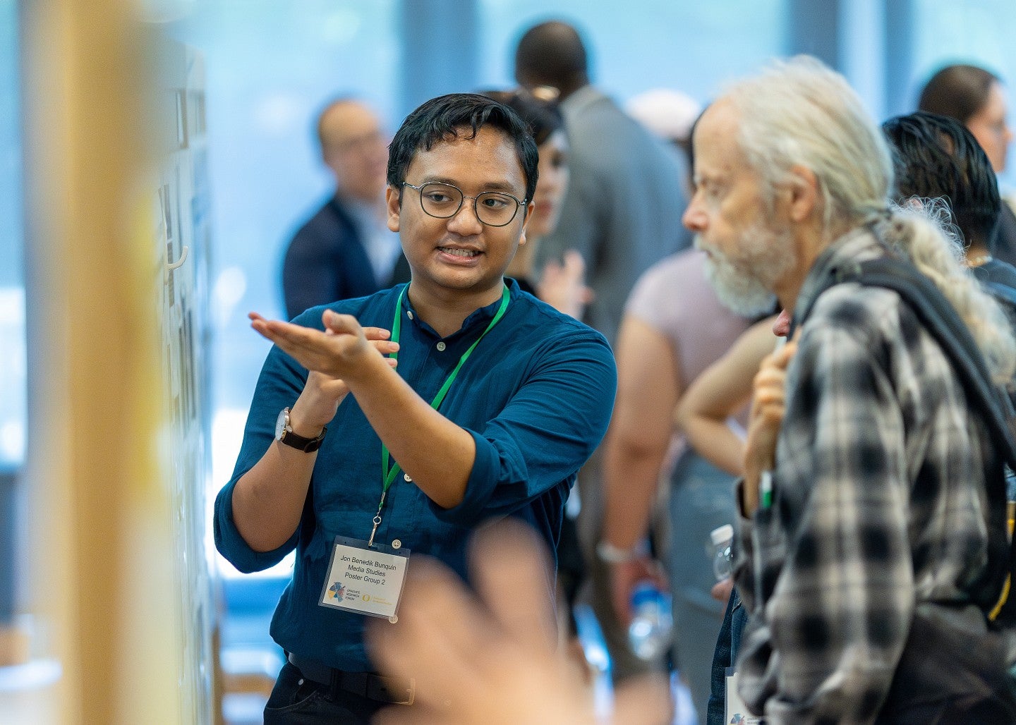 A graduate student referencing their poster to present their research.