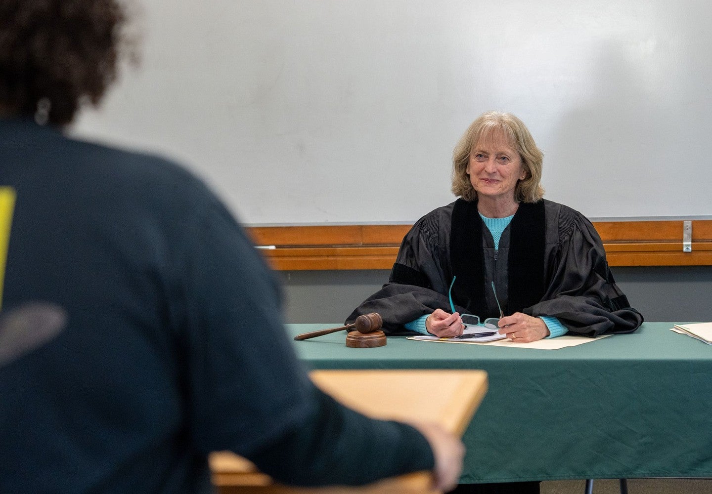 Suzanne Rowe wears a black judge's robe and sits behind a desk.
