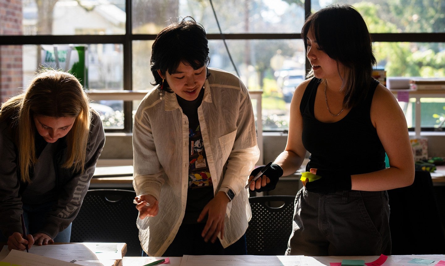 Three graduate students work together at a table.