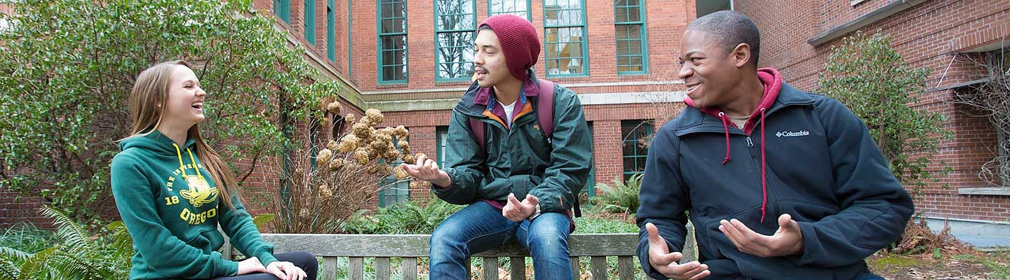 Three students talking while sitting on a bench Three students talking while sitting on a bench