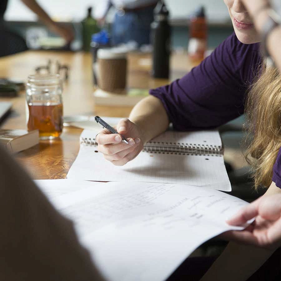 People writing in notebooks while studying at a table