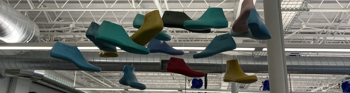 Colorful shoe shapes hang overhead from an industrial ceiling.