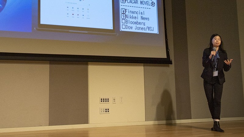 Presenter holds a microphone and lectures.