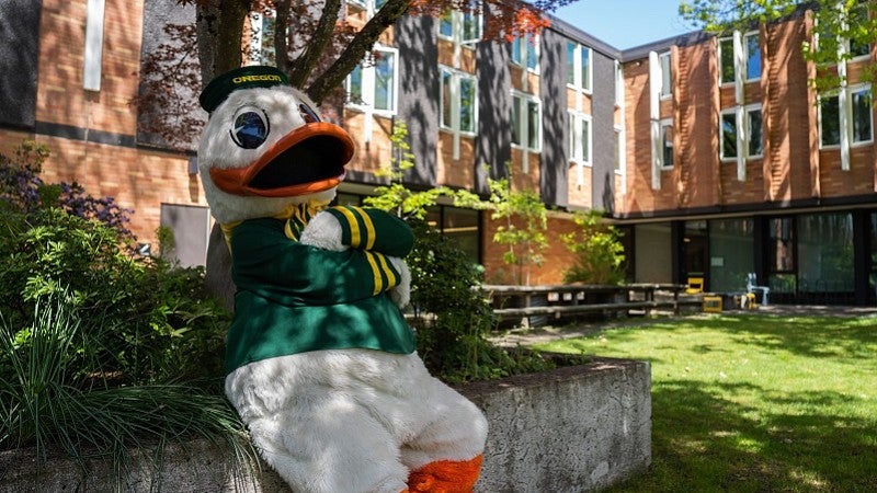uo duck mascot sitting in front of a residence hall