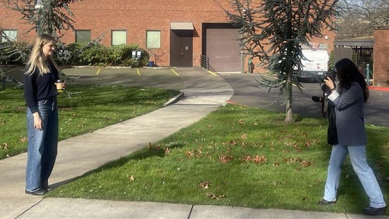 One person taking a photo of another outside.