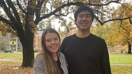 Emily Arnesen and Kyutaro Matsuzawa stand together under autumn foliage.