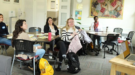 A group of graduate students listening to a speaker 