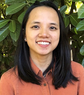 Ngan Tran has shoulder length dark hair and is wearing an orange button down shirt.