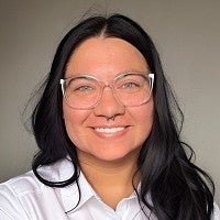 Smiling woman with long dark hair and glasses.