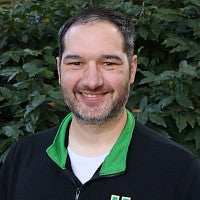 Alex has short dark hair and is smiling.